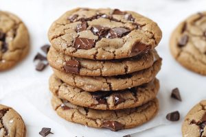 Stack of chocolate chip cookies sitting on top of whit parchment paper.
