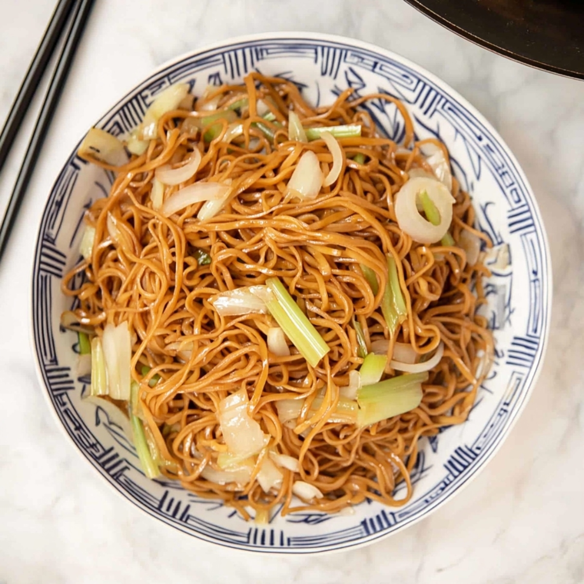 A serving of chow mein noodles in a Chinese designed bowl.
