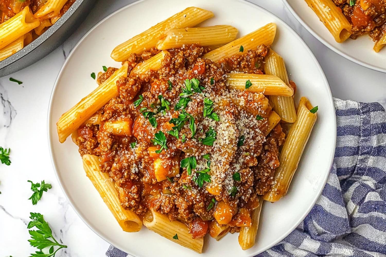 Penne bolognes in tomato sauce served in a white plate.