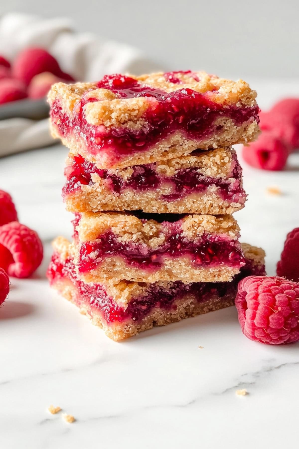 A stack of raspberry jam bars on a white marble countertop.