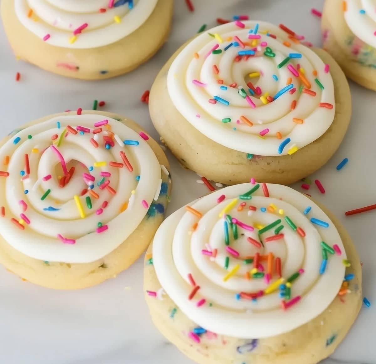 A close up Crumbl birthday cake cookies with spiral frosting and candy sprinkles.