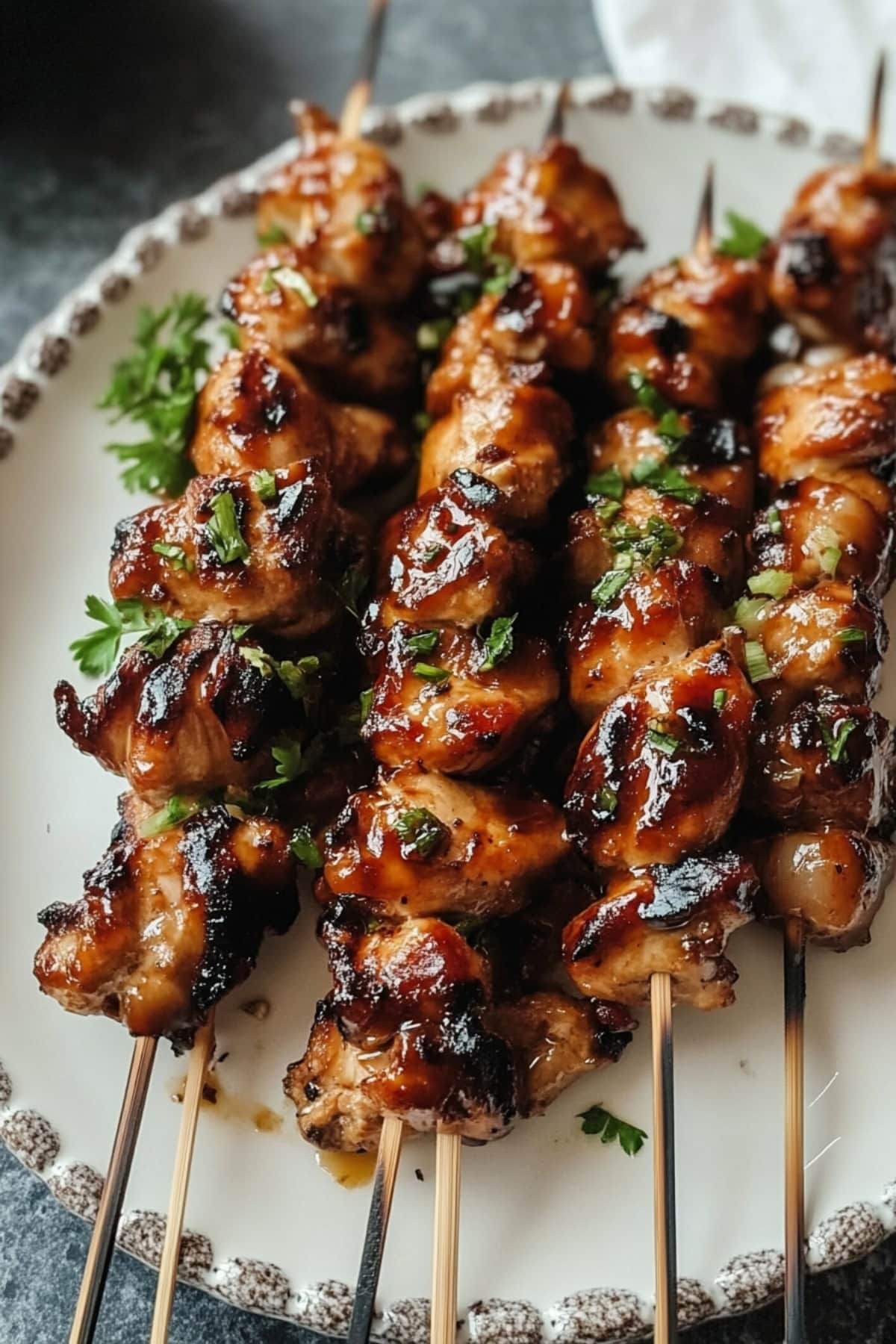 Teriyaki chicken skewers coated in a glossy sauce, garnished with green onions, top view