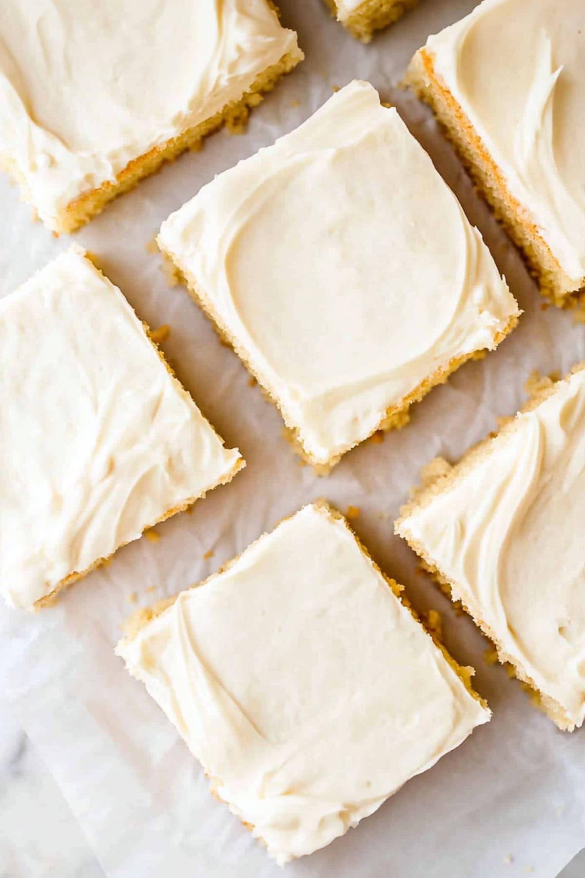 Square slices of vanilla buttermilk cake on top of parchment paper.