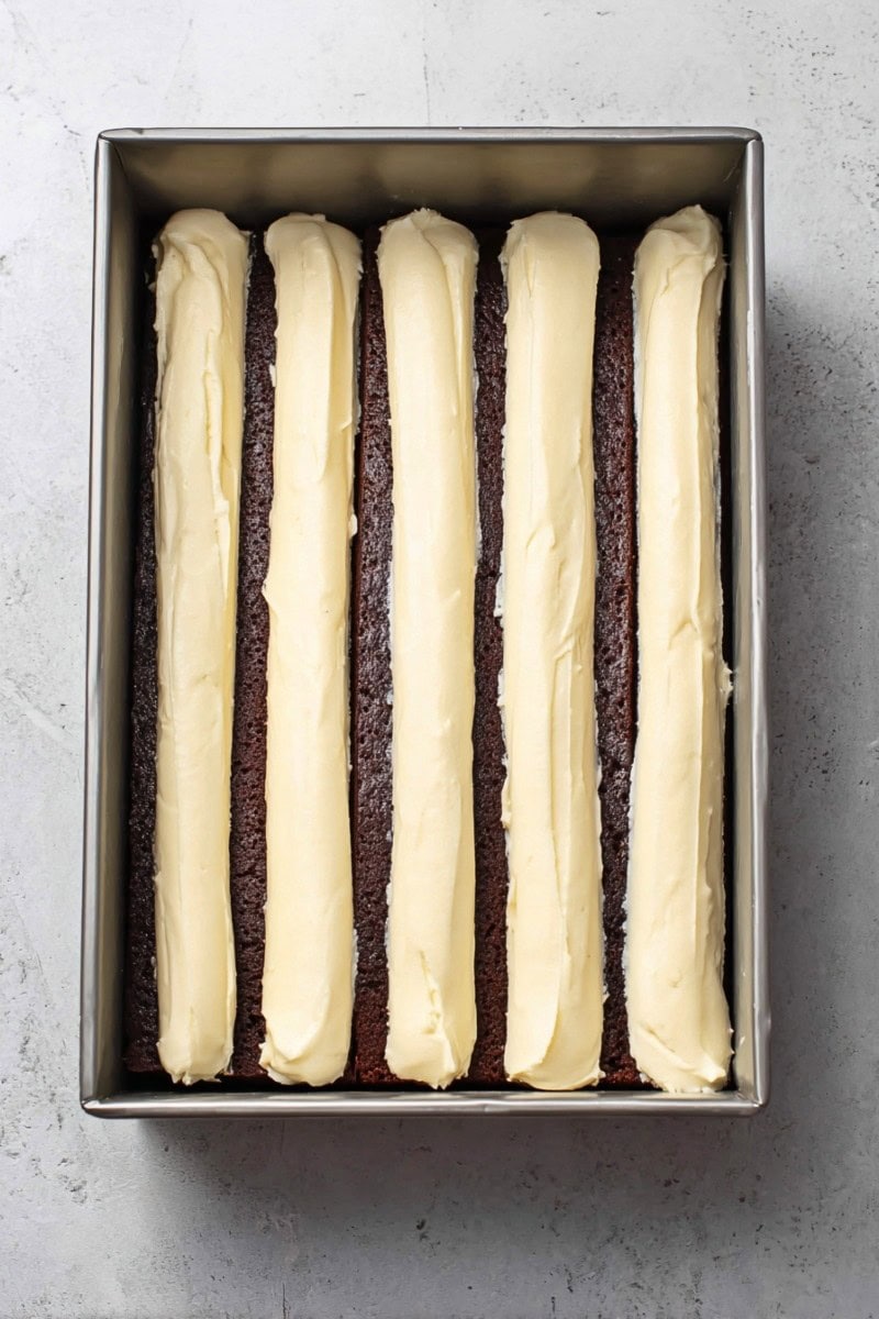A chocolate sheet cake with thick, rows of piped vanilla buttercream across the top.