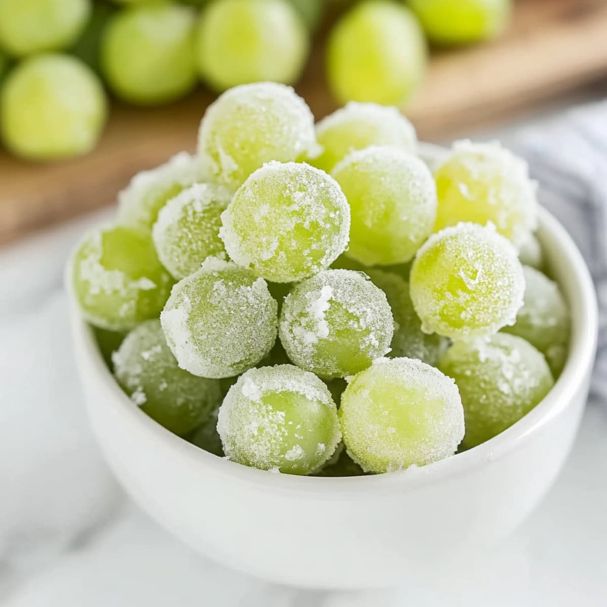 Frozen grapes in a white bowl.