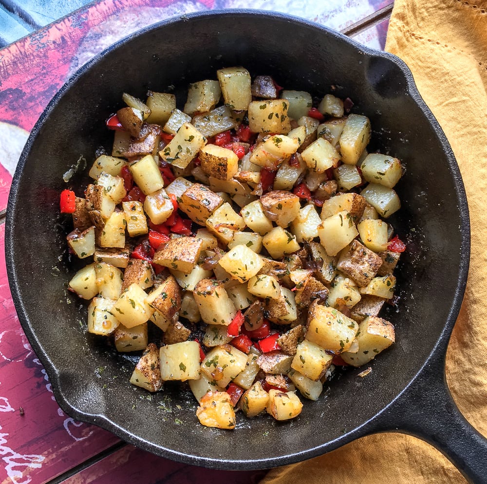 Diced potatoes sautéed with red pepper and onion on a skillet.